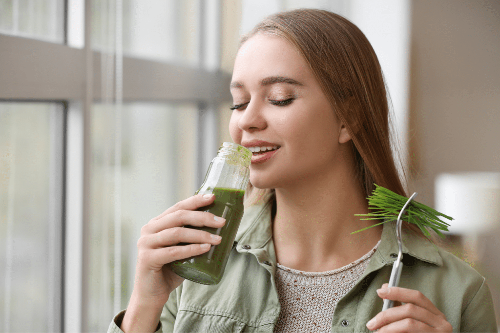 a woman with a wheatgrass in hand trying to show the health benefits of wheatgrass juice